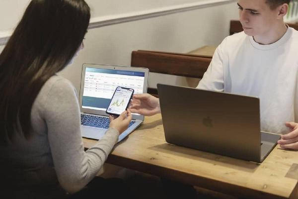 Una mujer y un hombre -traders- analizando gráficos de mercados en sus computadoras.