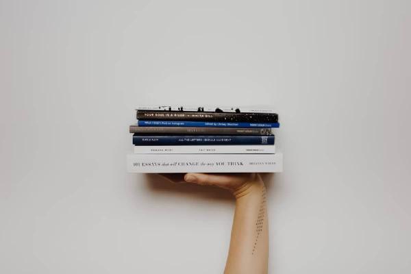 Una mano sosteniendo varios libros de trading.