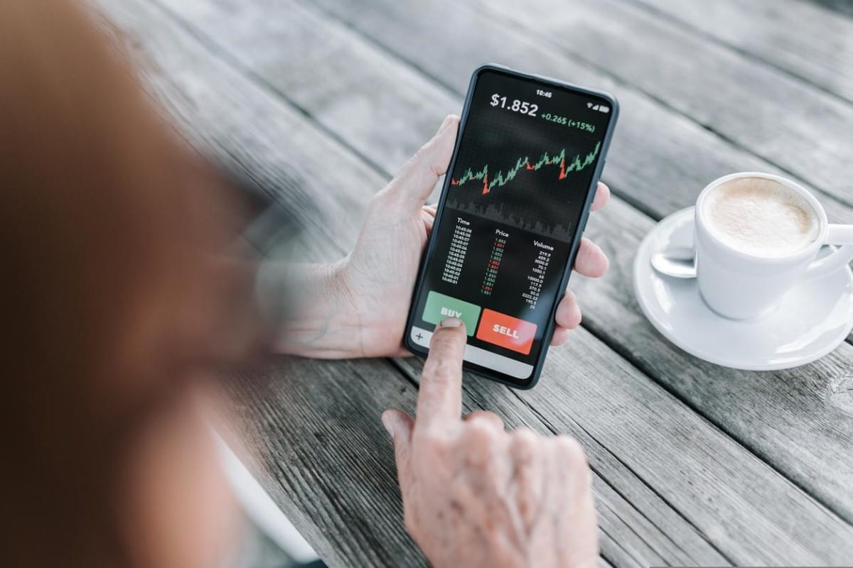 Una persona revisa gráficos en su celular para analizar cómo invertir en la bolsa.