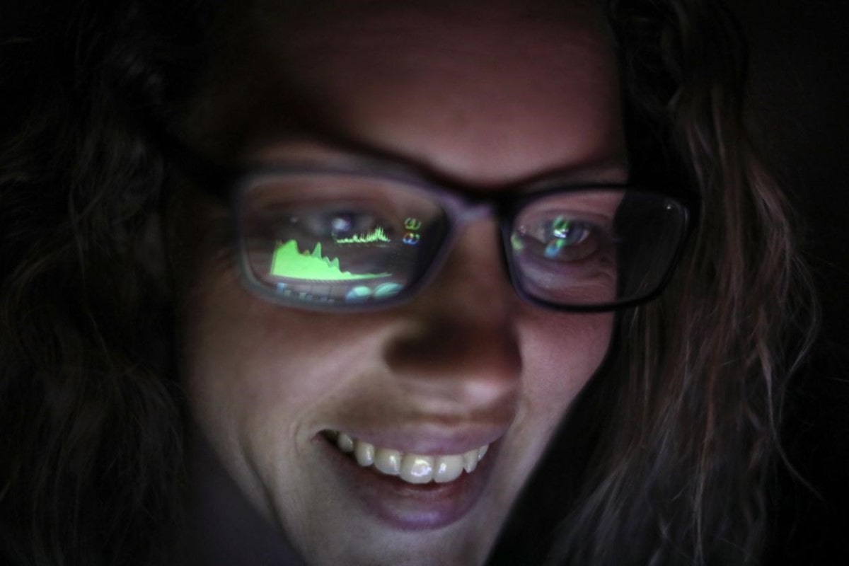 Los lentes de una trader reflejan el gráfico de tendencia que observa en una pantalla.