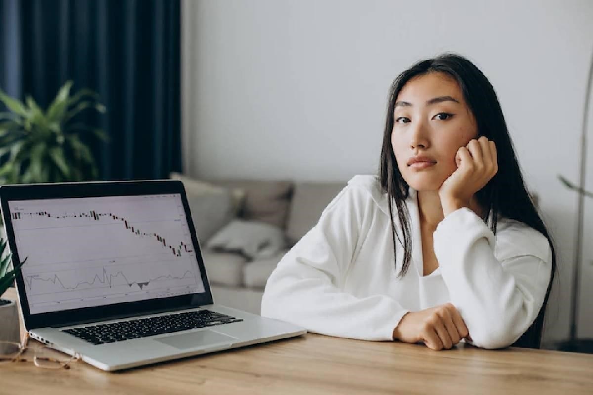 Una mujer junto a la pantalla de su computadora pensando en sus inversiones.