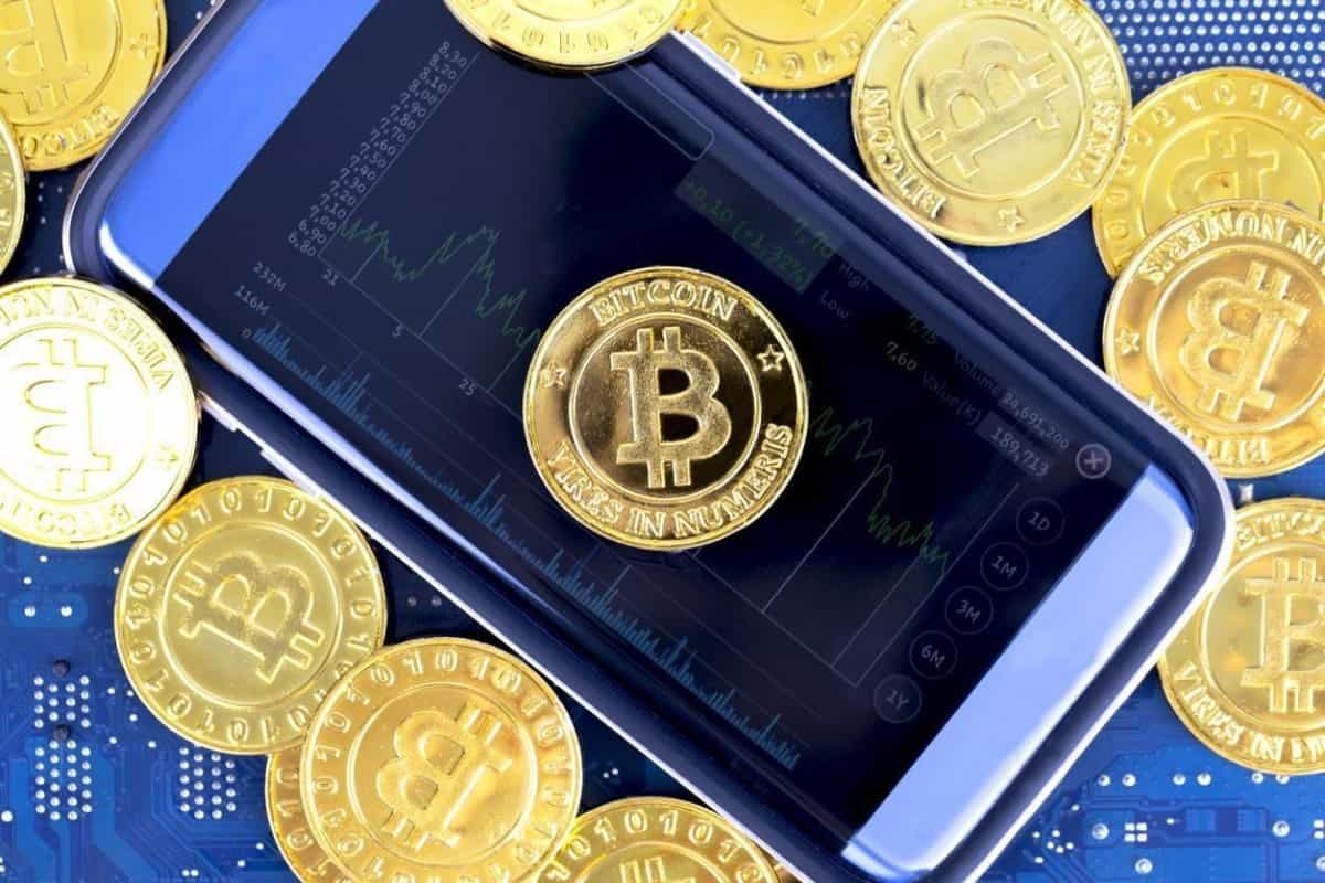 Imagen de un BTC en la pantalla de un celular. Conoce cómo invertir en Bitcoin.