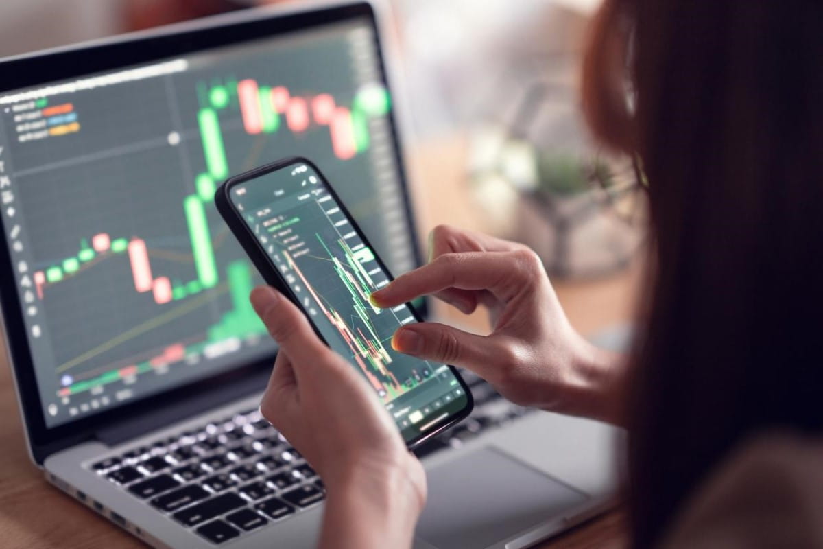 Trader analiza tendencias en su celular, para saber cómo invertir en criptomonedas.