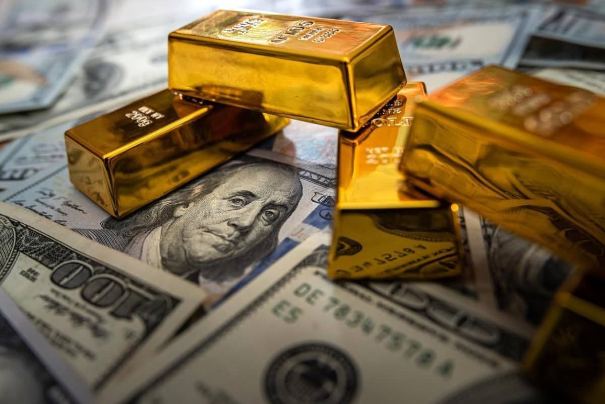 Bloques de oro sobre billetes de dólar. Descubre las tendencias para invertir en materias primas