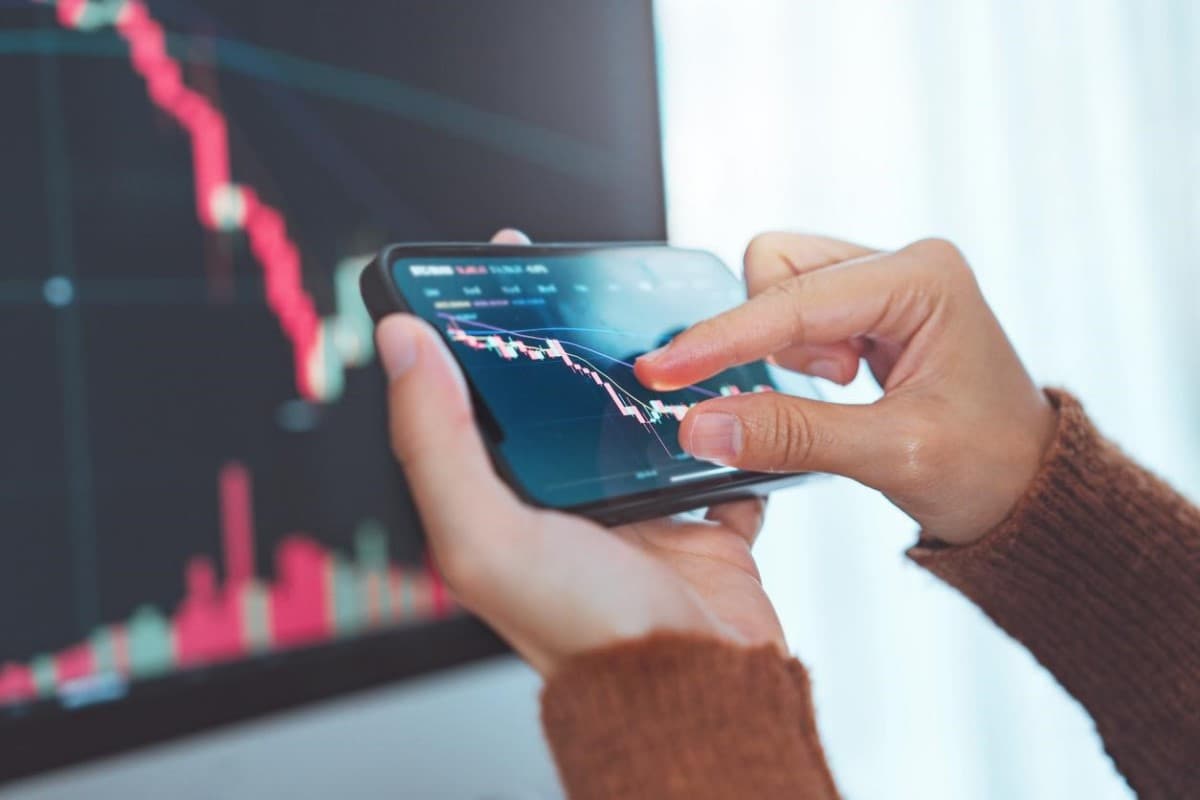 Una mujer analiza en su celular los precios de Litecoin, Bitcoin y otras criptomonedas.