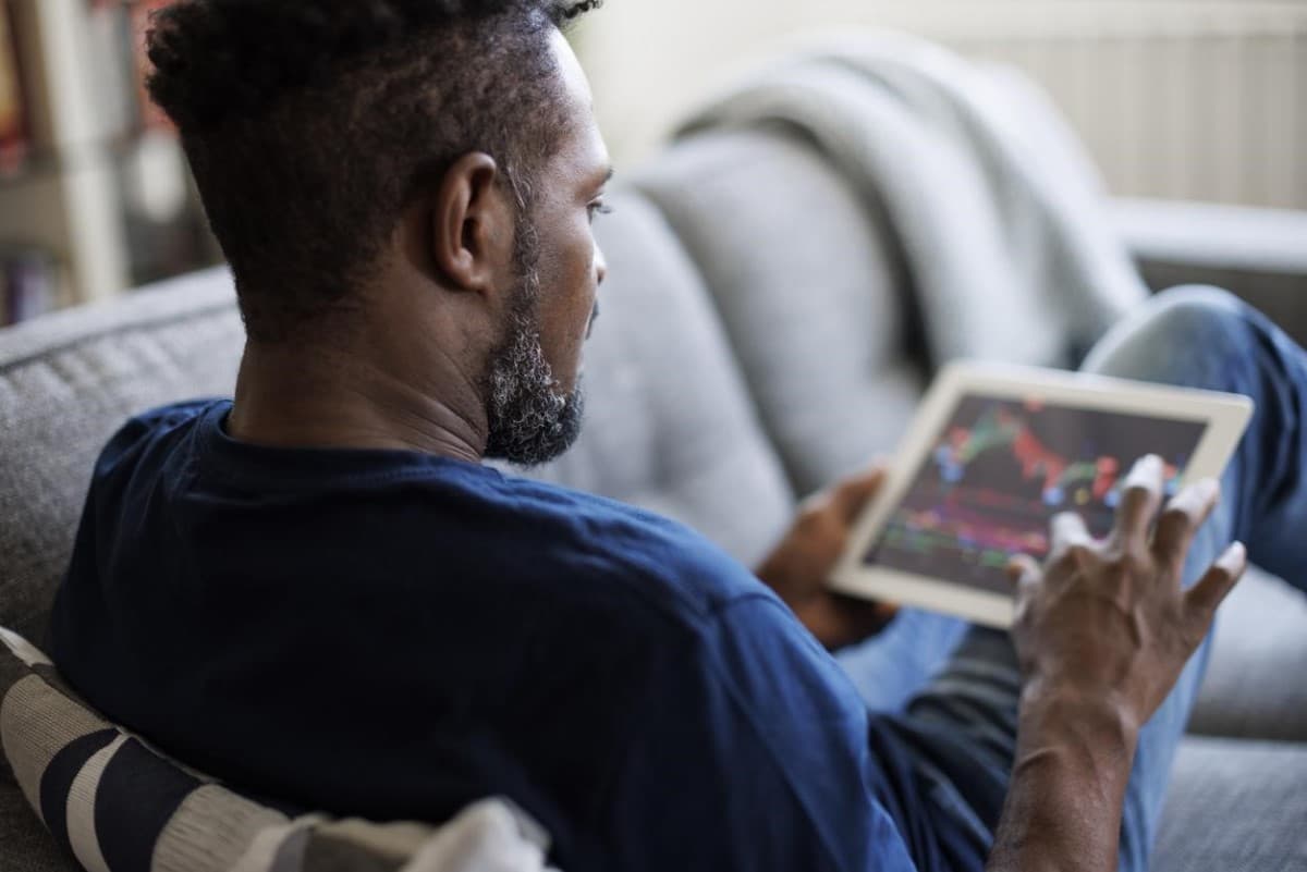 Trader analiza tendencias en su tablet para definir cuál es la mejor criptomoneda para invertir.