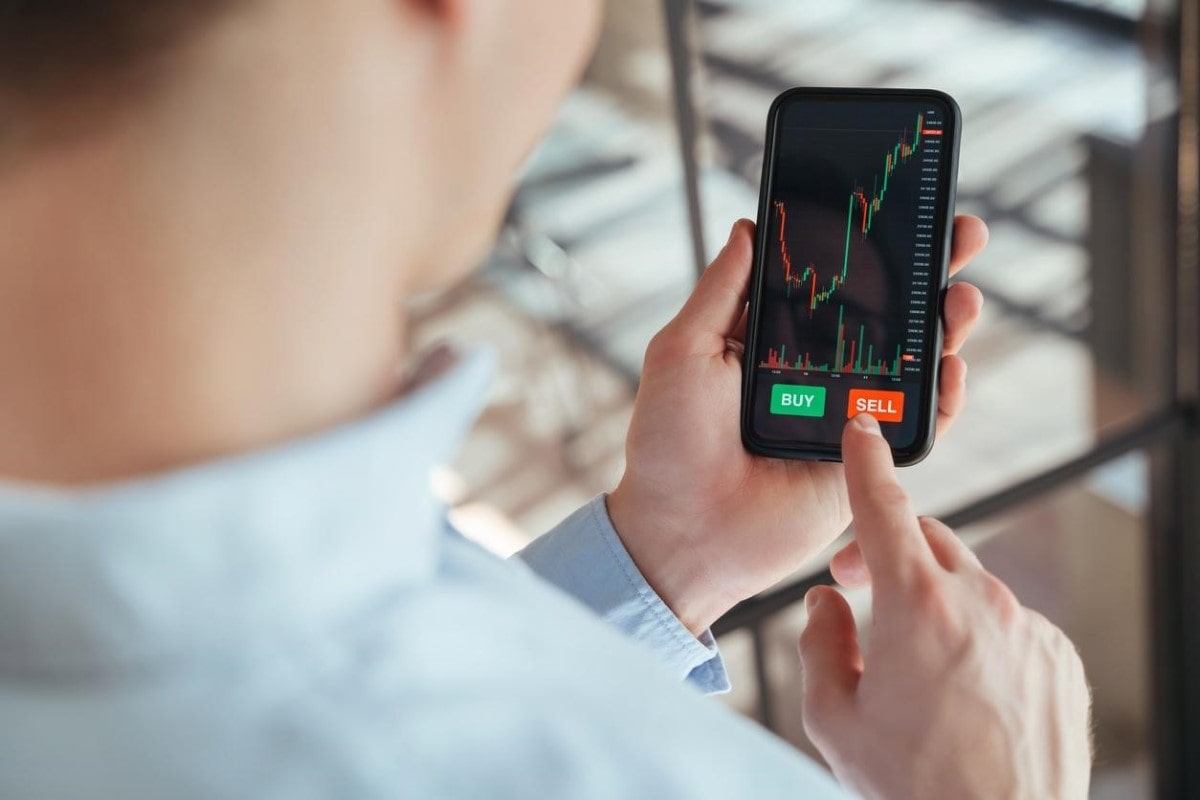 Comerciante que aprendió qué es un trader, opera en línea desde su celular.