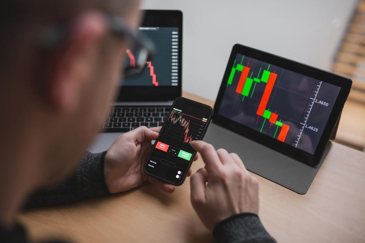 Un hombre, que es trader profesional, opera desde varios dispositivos móviles.