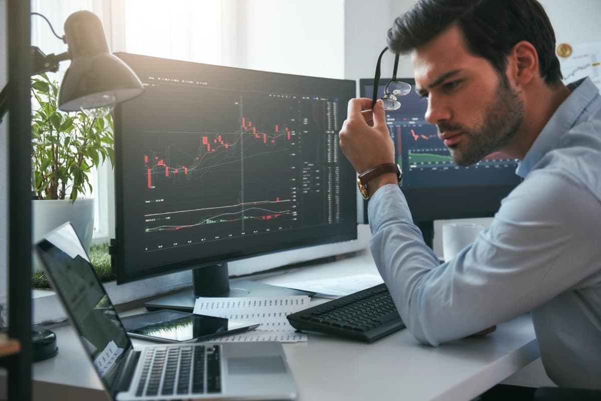Joven revisa en su computador qué son futuros en trading y sus gráficos de tendencia.