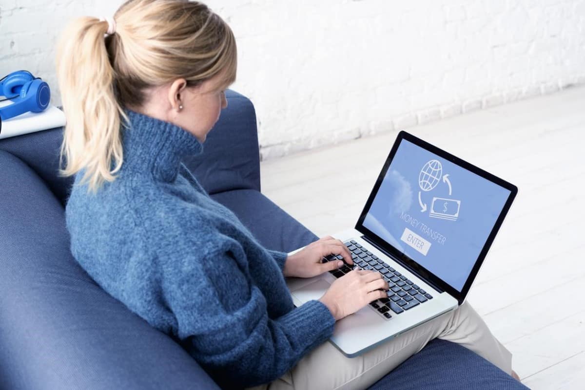 Una mujer transfiere dinero de remesas a través de banca virtual en su laptop.