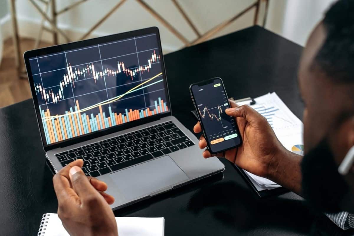 Un inversionista práctica en su computadora y en su celular trading de alta frecuencia.