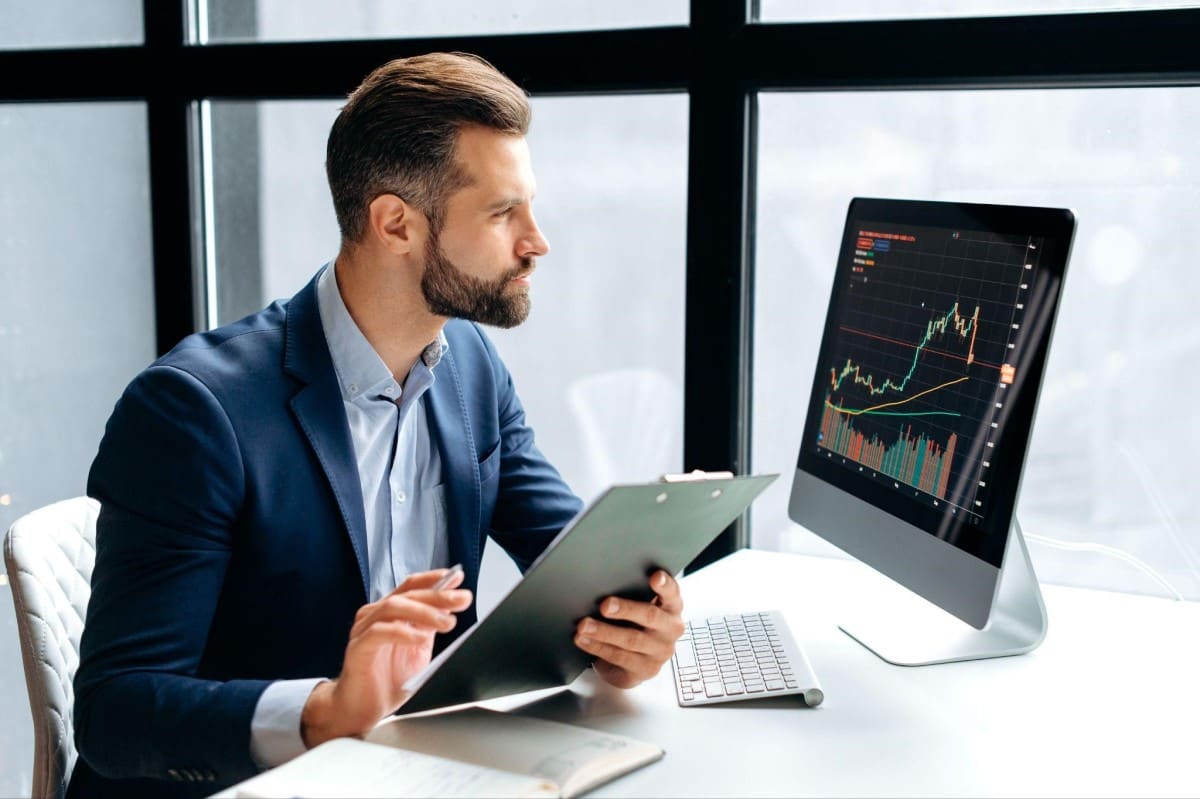 Inversionista revisa en su computadora un gráfico de triángulo ascendente en trading.