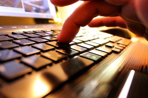 Persona presionando teclas en una computadora para investigar qué es el trading.