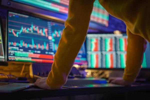 Trader revisa gráficos en sus monitores y analiza si abrir una orden Buy Limit.