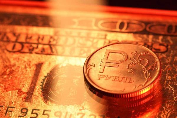 Una moneda de un rublo ruso sobre un billete de 100 dólares estadounidenses.