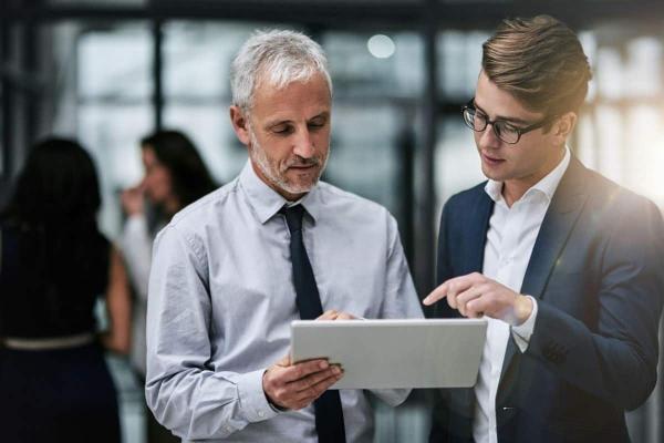 Dos inversionistas analizan en una tablet información sobre fondos de cobertura.