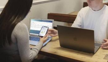 Una mujer y un hombre -traders- analizando gráficos de mercados en sus computadoras.