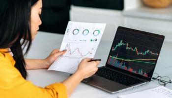 Trader revisa en una hoja y en su computadora gráficos de ETFS más rentables.