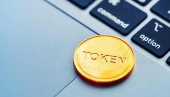 Una moneda Token sobre una computadora. Conoce qué es la tokenización de activos.