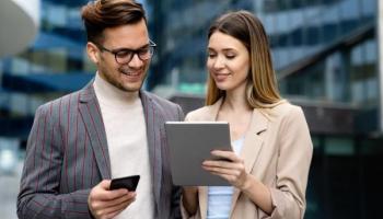 Dos personas consultan en una tablet cómo comprar acciones de una empresa.