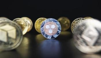 Un ripple y otras crypto sobre una superficie oscura. Con cualquiera de ellas se puede practicar el minado de criptomonedas.