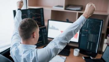 Un inversor celebra frente a pantallas tras implementar con éxito la estrategia DCA.