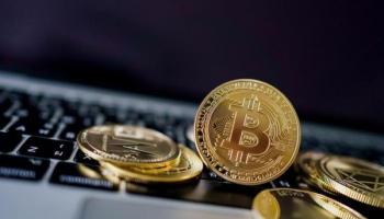  Bitcoins y otras criptomonedas sobre un ordenador. Descubre qué son las feels en la minería crypto.