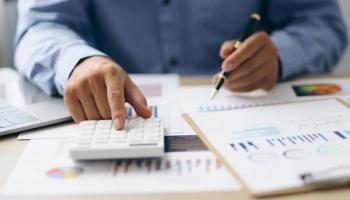 Un hombre hace cálculos y analiza su presupuesto. Un paso esencial en la educación financiera.