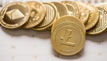 Una criptomoneda Litecoin junto a otras monedas digitales sobre un calendario.