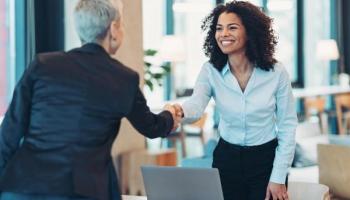 Una asesora bancaria saluda a una cliente. Nubank y acciones pertenecen a este importante sector.