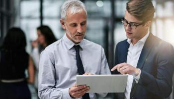 Dos inversionistas analizan en una tablet información sobre fondos de cobertura.