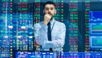 Trader observa datos y números proyectados en una pantalla y analiza estrategias de trading cuantitativo a aplicar.