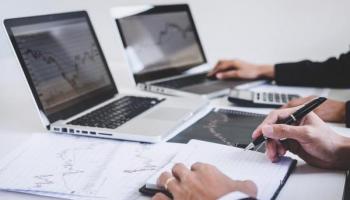 Inversionistas analizan en sus laptops gráficas y tendencias de mercados emergentes.